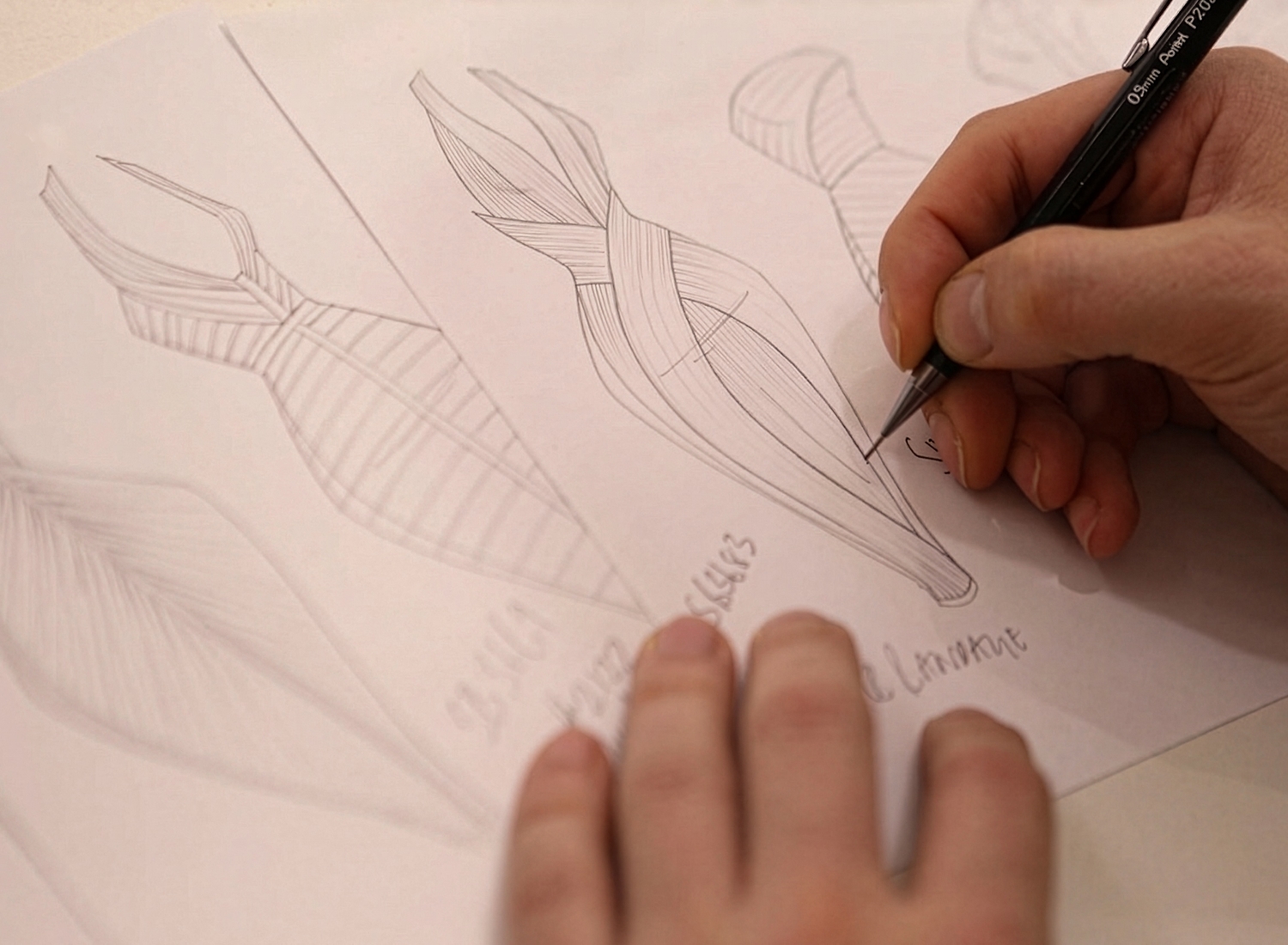 Designer's hands sketching a draped garment design in pencil on paper